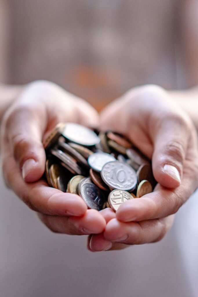 Crop anonymous person demonstrating heap of coins in hands demonstrating concept of savings